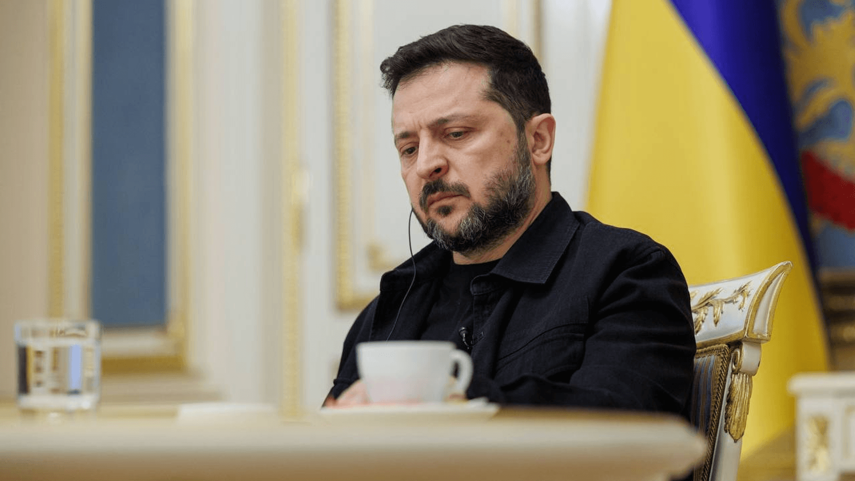 Володимир Зеленський за столом на тлі прапора України